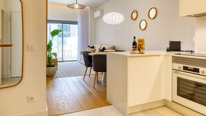 A modern kitchen with a central island, a dining area with chairs, and a large window. - Funchal Acqua Blue 3O, a Home in Madeira (Funchal)