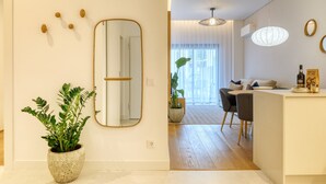 A modern living room with a large mirror, a potted plant, and a dining area with a table and chairs. - Funchal Acqua Blue 3O, a Home in Madeira (Funchal)