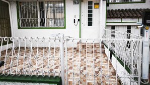 A building with a tiled roof, a white door with a window, and a metal gate. - Kuyay Yachi Hostel (Bogotá)