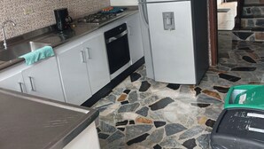 A kitchen with a refrigerator, stove, and tiled backsplash. - Kuyay Yachi Hostel (Bogotá)
