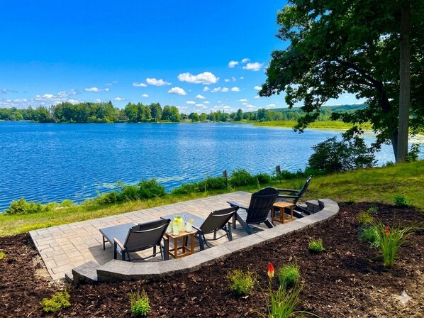 A lakeside patio with outdoor furniture and a view of the lake.