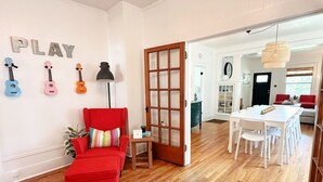 Una habitación con una silla roja, una puerta de madera, una mesa blanca y una pared con letras con forma de guitarra.