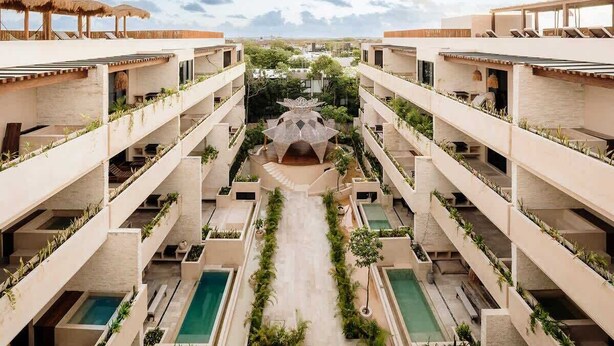 Un hôtel à plusieurs étages doté de piscines extérieures, d’une cour intérieure et de balcons ornés de plantes.
