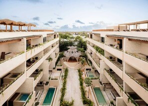 A multi-story hotel with outdoor pools, a central courtyard, and balconies with plants.