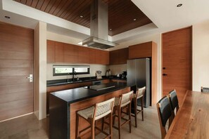 Una cocina moderna con una isla central, armarios de madera y un refrigerador grande.
