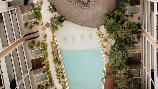 Uma área de piscina no terraço com duas piscinas, um espaço central para sentar e vegetação ao redor.