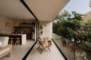 A modern interior with a balcony, wooden furniture, and a kitchen area. - K'Abax Jungle Apartment Beach Club Access (Tulum)