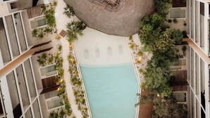 Ett poolområde på taket med två pooler, en central sittgrupp och omgivande grönska.