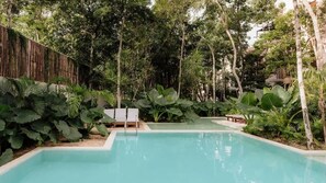 A swimming pool surrounded by lush greenery and a wooden fence. - Villa Coralia J2 Private Pools Beach Club Access (Tulum)
