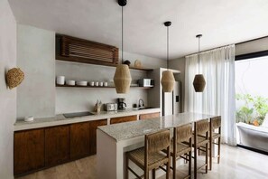 A modern kitchen with a central island, wooden cabinets, and pendant lights. - Villa Coralia J2 Private Pools Beach Club Access (Tulum)