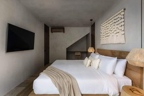 A modern bedroom with a large bed, a mounted TV, a wall-mounted macrame piece, and a staircase. - Villa Coralia J2 Private Pools Beach Club Access (Tulum)
