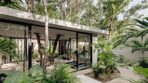 A modern building with a glass facade, surrounded by lush greenery and trees.