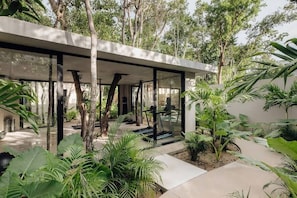 A modern building with a glass facade, surrounded by lush greenery and trees.
