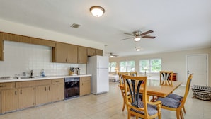 A spacious kitchen with wooden cabinets, a dishwasher, and a refrigerator. There is a dining area with a table and chairs. - Home 3 Mi to Homosassa Springs Wildlife State Park (Homosassa)