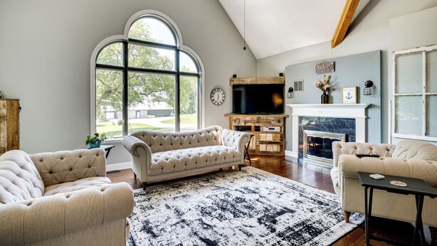 Un salón espacioso con un gran ventanal, chimenea y televisor.