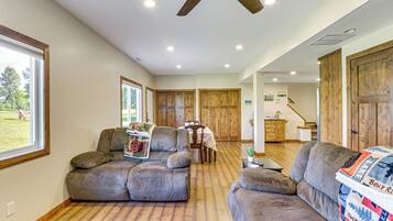 A spacious living room with two large sofas, a dining table, and wooden doors.