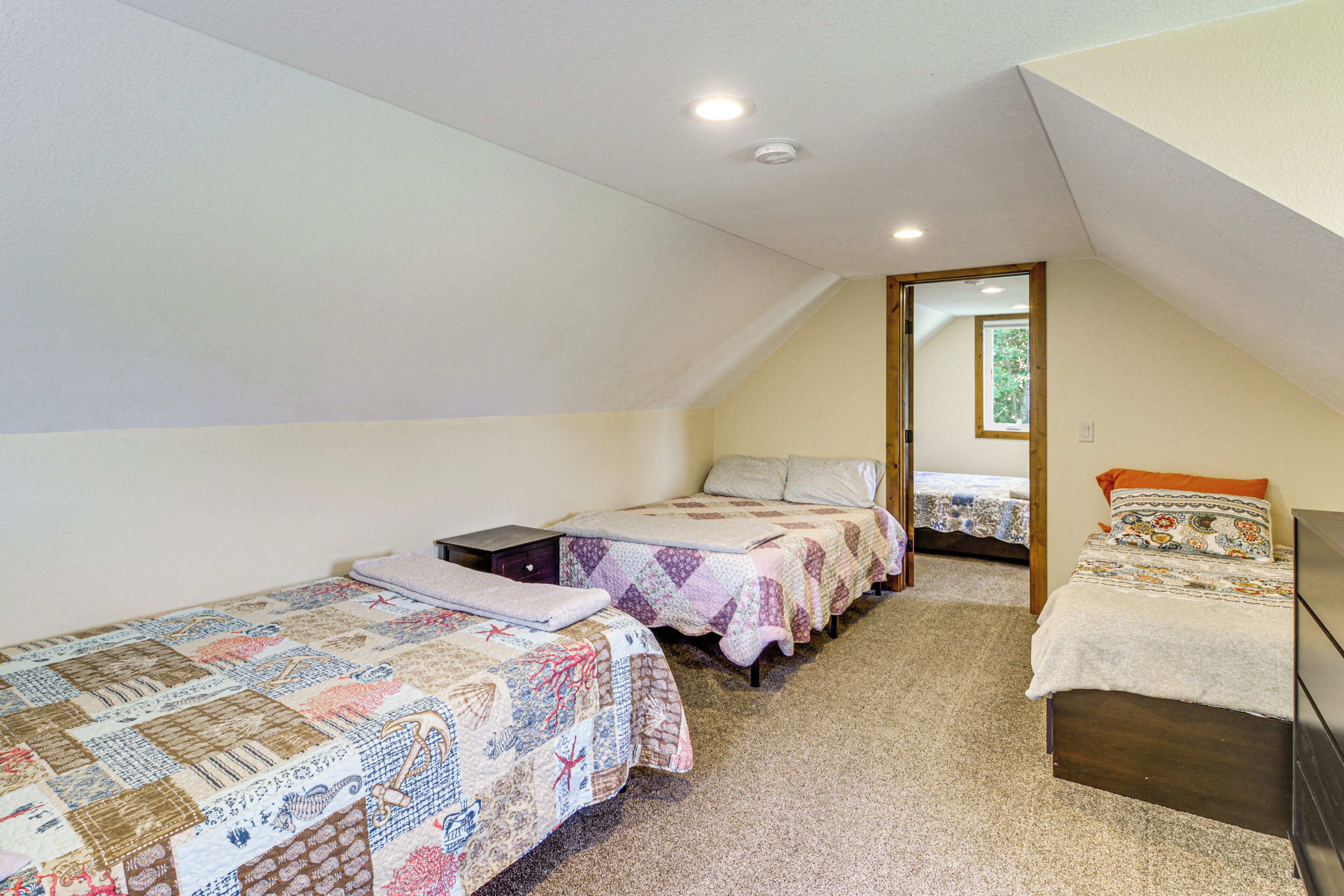 A bedroom with two beds, a wooden dresser, and a carpeted floor.