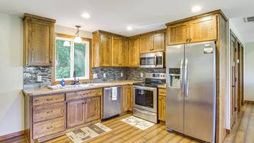 A kitchen with wooden cabinets, stainless steel appliances, and a stone backsplash.
