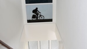 A staircase with a handrail, a window with a seagull, and a silhouette of a cyclist.