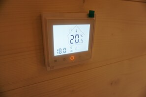 Un thermostat doté d’un écran numérique indiquant une température de 20,5 °C et un taux d’humidité de 18,0 %.