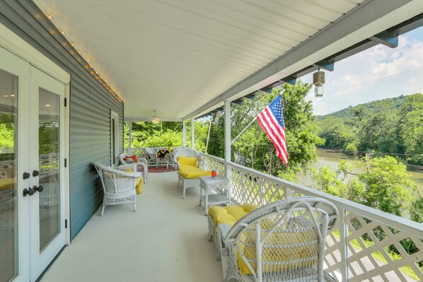 A covered porch with wicker furniture and an American flag. - River Views & Boat Launch Access: Huntingdon Home (Huntingdon)