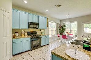 Una cocina con gabinetes color turquesa, una estufa de acero inoxidable y una encimera de granito.