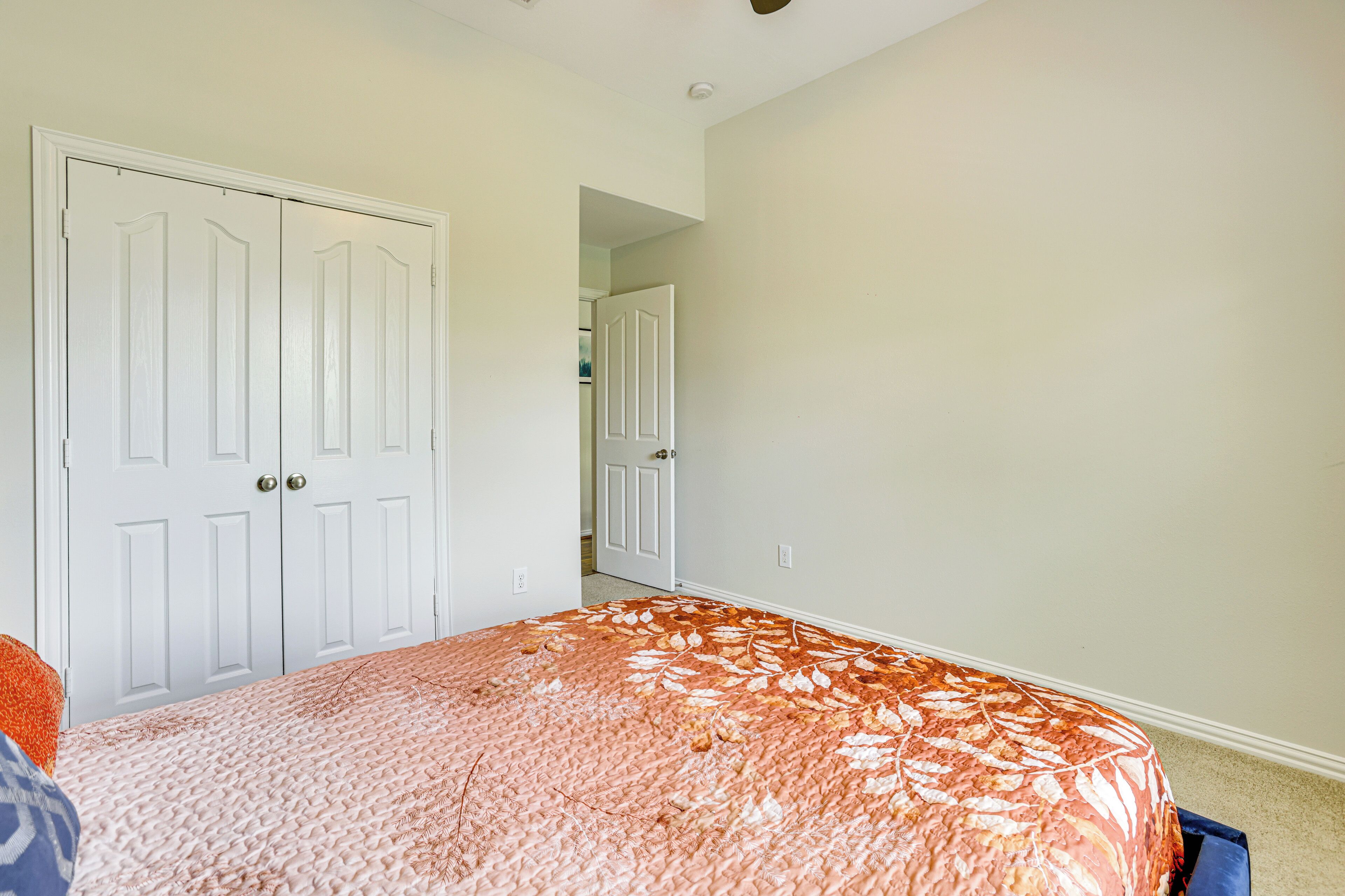 Une chambre à coucher avec un lit, deux portes blanches et un couloir menant à une autre pièce.