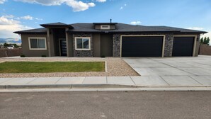 A modern two-story house with a stone facade, a garage, and a well-maintained lawn. - Comforable 3 bed 3 bath home (Cedar City)