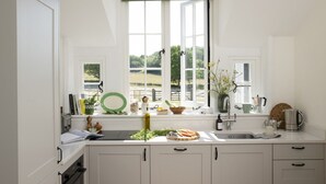 A kitchen with a large window, a sink, and various kitchen items on the counter.