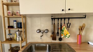 Una cucina con un lavello in acciaio inossidabile, scaffali in legno e utensili pensili.