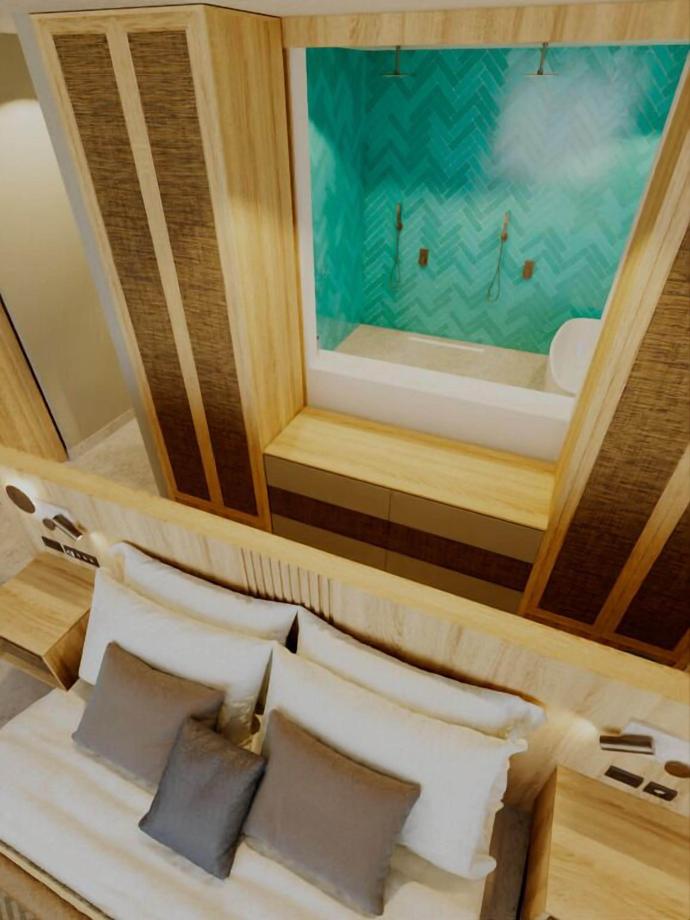 A room with a bed, a small seating area, and a view of a bathroom with a herringbone patterned wall.