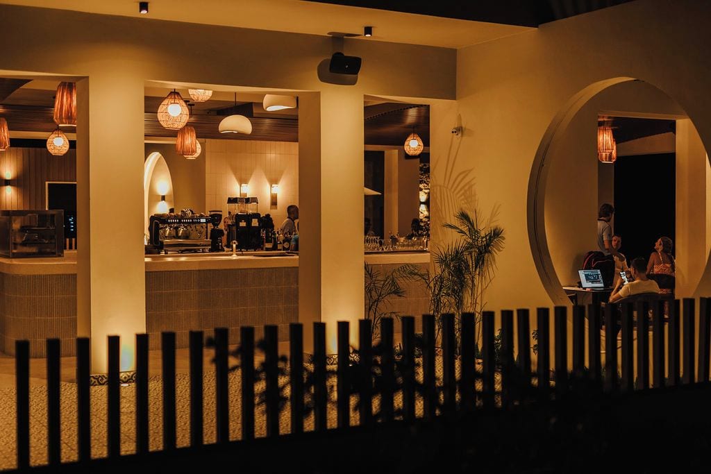 Een hotellobby met een receptiebalie, een zithoek en een rond raam.