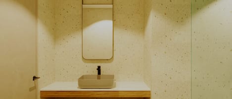A bathroom with a wooden vanity, a mirror, and a tiled wall.