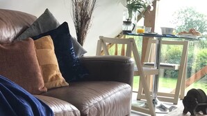 A cozy living room with a leather sofa, a glass coffee table, and a view of the garden.