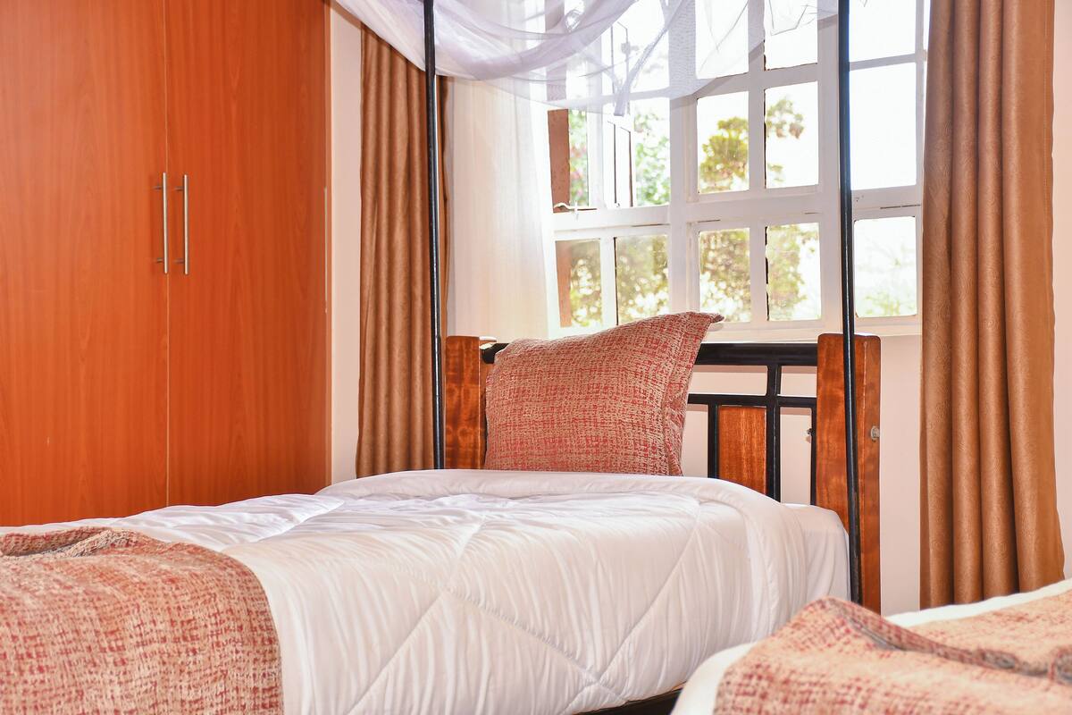 A bedroom with a bed, a window, curtains, and a wardrobe.