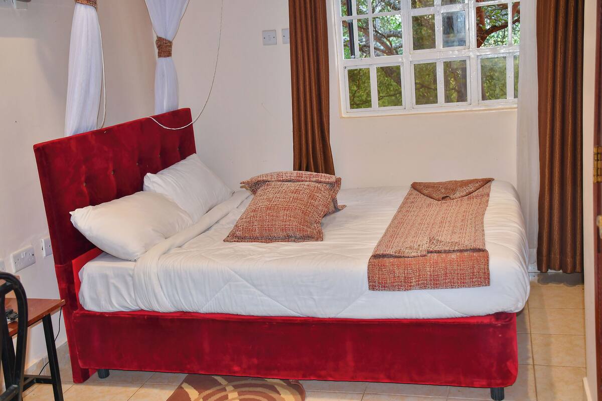 A bed with a red headboard, white bedding, and two brown decorative pillows.