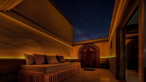 Un espacio al aire libre acogedor con vista a un cielo estrellado, un banco de madera y una puerta grande de madera.