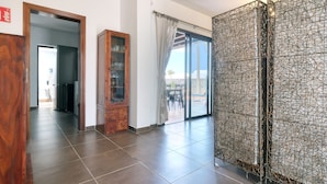 A spacious room with a large sliding glass door leading to a balcony, a wooden cabinet with glass doors, and a patterned metal partition.