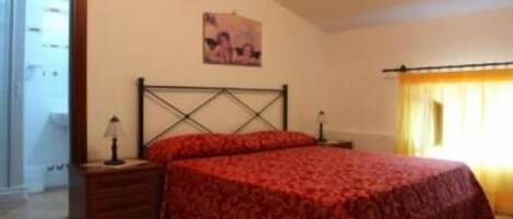 A bedroom with a large bed, a nightstand, a lamp, and a painting on the wall.
