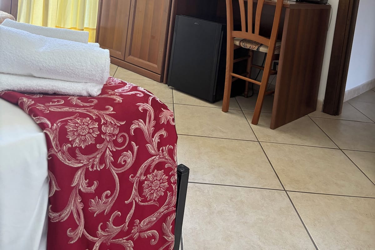 Habitación de hotel con cama, escritorio, computadora, silla, armario y espejo.