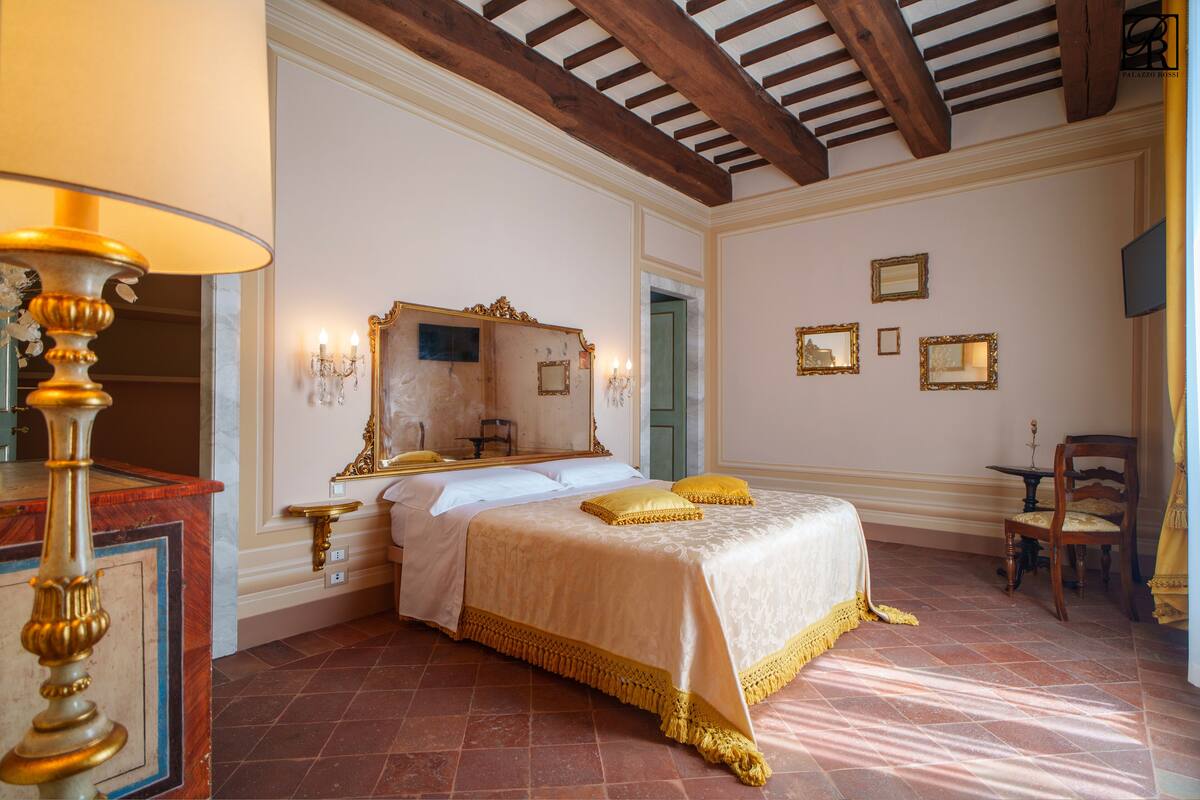 A bedroom with a large bed, a mirror, and a chandelier.