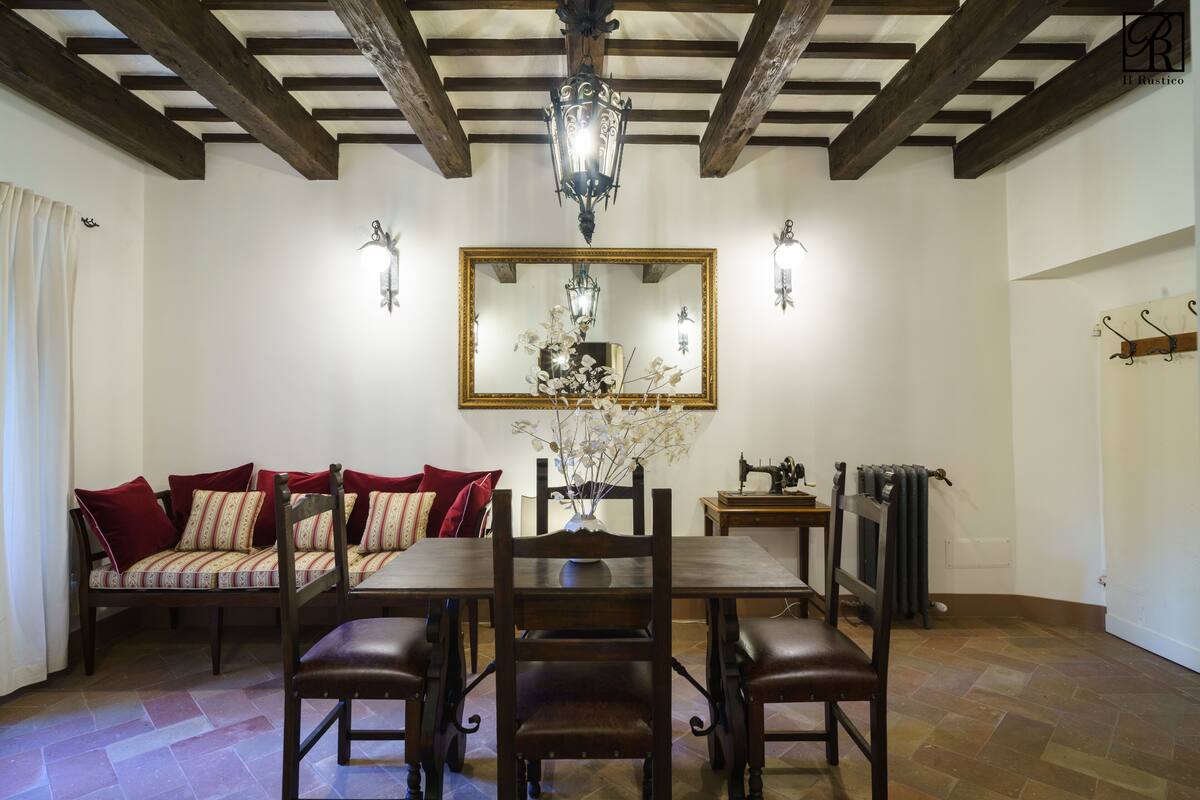 A dining area with a wooden table and chairs, a chandelier, and a mirror above the table.