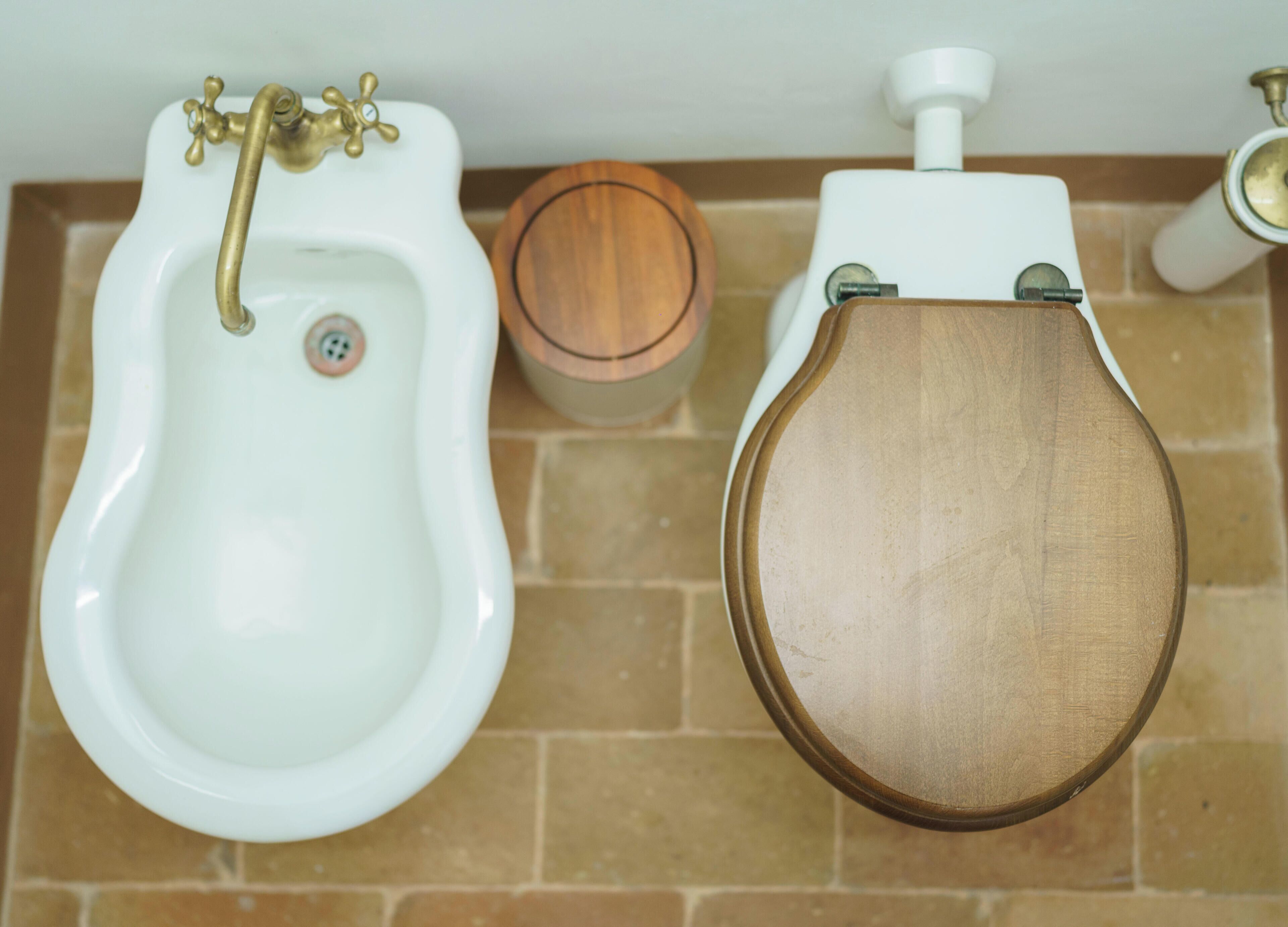 Un baño con un orinal blanco, un asiento de váter de madera y un dispensador de papel higiénico.