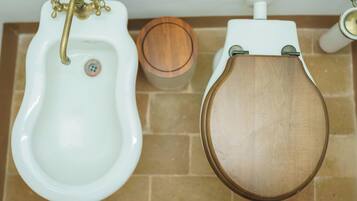 Un baño con un orinal blanco, un asiento de váter de madera y un dispensador de papel higiénico.