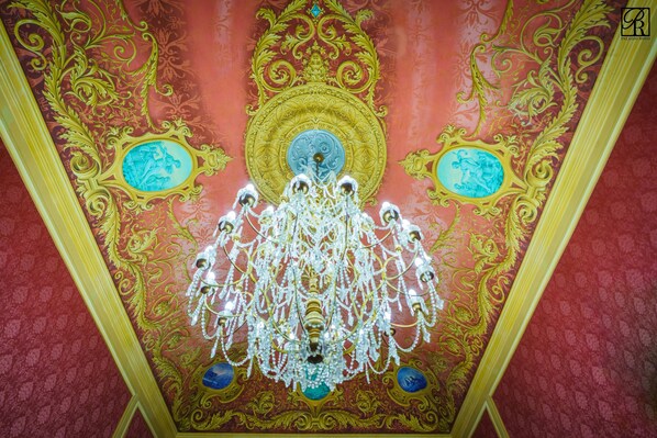 A ceiling with ornate gold and blue designs, a chandelier, and a central medallion. - Palazzo Rossi (Sarnano)