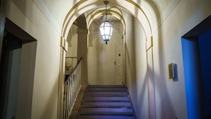 Un pasillo con escaleras, una lámpara y una puerta al final.