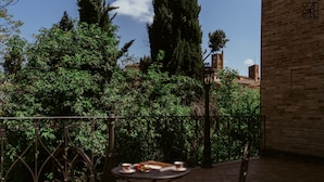 Un patio con una mesa y sillas, rodeado de vegetación y un muro de ladrillo.