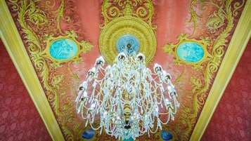 A ceiling with ornate gold and blue designs, a chandelier, and a central medallion.