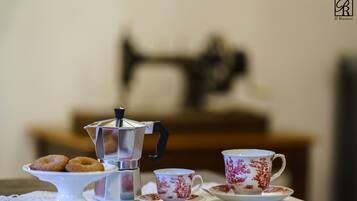 A table with a coffee pot, a cup, and a plate with donuts.