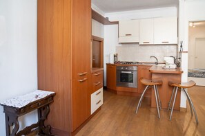 Una cocina con armarios de madera, una estufa y dos taburetes de bar.